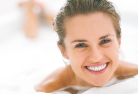 smiling young woman laying in bathtubの写真素材