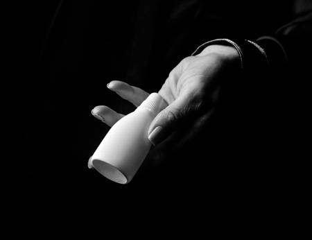 Black Mania. woman hand isolated on black showing bottle of medical dropsの写真素材