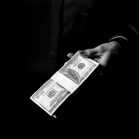 Black Mania. female hand isolated on black showing pack of dollarsの写真素材