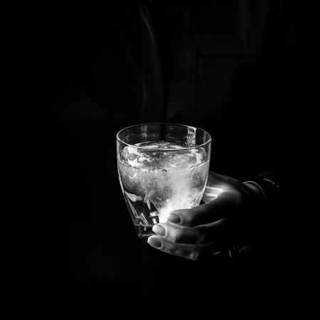 Black Mania. woman hand isolated on black background showing glass of water with effervescent tabletの写真素材