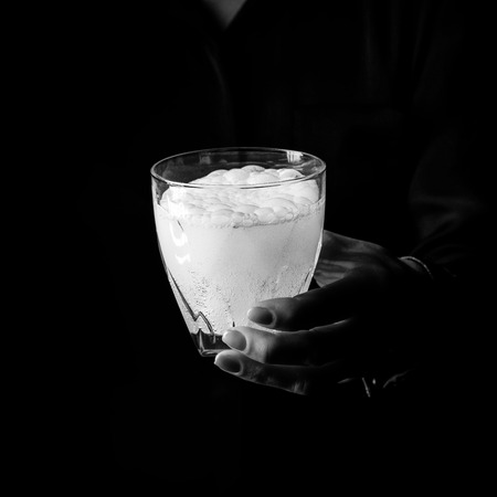 Black Mania. woman hand isolated on black background showing glass of water with effervescent tabletの写真素材