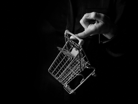 Black Mania. woman hand isolated on black showing mall shopping cartの写真素材
