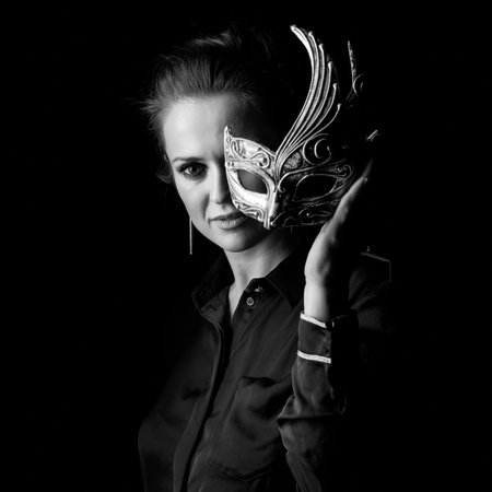 ?oming out into the light. Portrait of woman in the dark dress isolated on black background holding...
