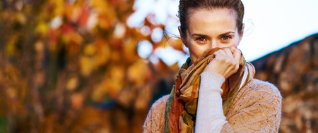 Young woman hiding in scarf in autumn eveningの写真素材