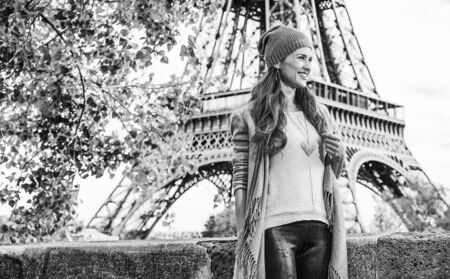 Autumn getaways in Paris. Full length portrait of smiling young tourist woman on embankment near Eiffel tower in Paris, France having excursionの写真素材