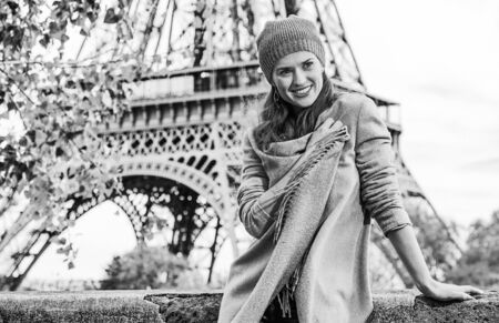 Autumn getaways in Paris. Portrait of happy young elegant woman on embankment near Eiffel tower in Paris, France having walking tourの写真素材