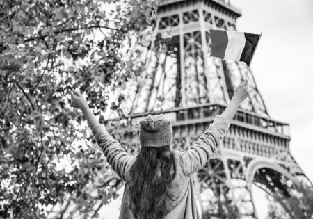 Autumn getaways in Paris. Seen from behind young elegant woman on embankment in Paris, France rising flagの写真素材
