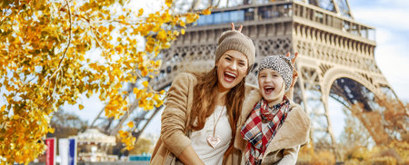 Autumn getaways in Paris with family. Portrait of happy mother and child travellers on embankment in Paris, France having fun timeの写真素材