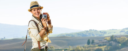 Discovering magical views of Tuscany. smiling active woman hiker in hat with bag hiking in Tuscany...