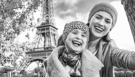 Autumn getaways in Paris with family. happy mother and child travellers on embankment near Eiffel tower in Paris, France taking selfie while sitting on the parapetの写真素材