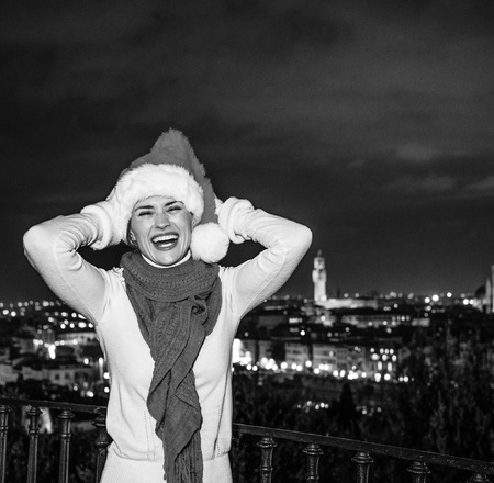 Trip full of inspiration at Christmas time in Florence. Portrait of smiling young woman in Christmas hat at Piazzale Michelangelo in Florence, Italyの写真素材