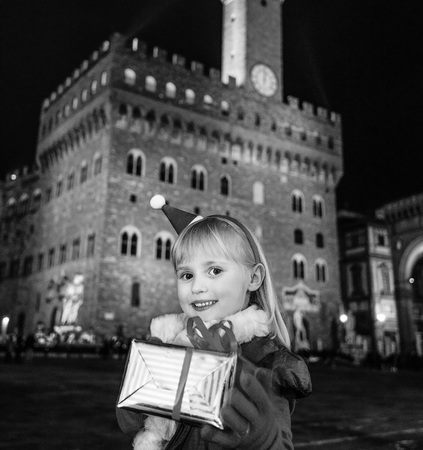 Trip full of inspiration at Christmas time in Florence. Portrait of smiling child with Christmas present box against Palazzo Vecchio in Florence, Italyの写真素材