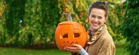 Trick or Treat. smiling modern woman on Halloween outdoors showing pumpkin Jack OLanternの写真素材