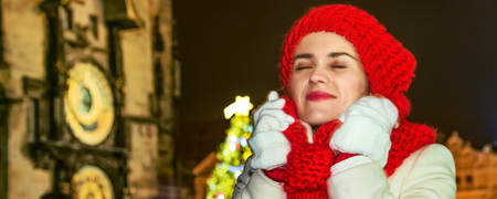 Magic on streets of the old town at Christmas. Portrait of smiling modern tourist woman in red hat and scarf at Christmas on Old Town Square in Prague Czech Republicの写真素材