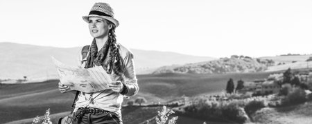 Discovering magical views of Tuscany. adventure woman hiker with bag hiking in Tuscany with map looking into the distanceの写真素材