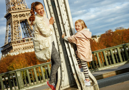 Year round fit & hip in Paris. smiling healthy mother and daughter in sport style clothes on Pont de Bir-Hakeim bridge in Paris having fun timeの写真素材