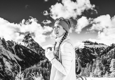 Winter on higher level of fun. smiling young tourist woman against mountain scenery in South Tyrol, Italy with thermos travel mugの写真素材
