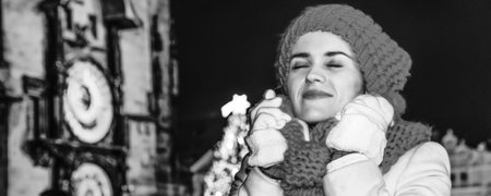 Magic on streets of the old town at Christmas. Portrait of smiling modern tourist woman in red hat and scarf at Christmas on Old Town Square in Prague Czech Republicの写真素材