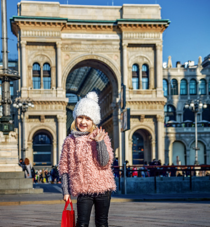 Rediscovering things everybody love in Milan. Full length portrait of happy modern girl with red shopping bag at Piazza del Duomo in Milan, Italy handwavingの写真素材