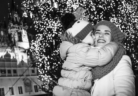 Magic on streets of the old town at Christmas. happy modern mother and daughter tourists at Christmas in Prague Czech Republic huggingの写真素材