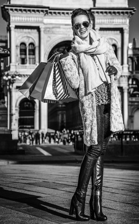 Rediscovering things everybody love in Milan. Full length portrait of happy modern tourist woman with shopping bags at Piazza del Duomo in Milan, Italy standingの写真素材