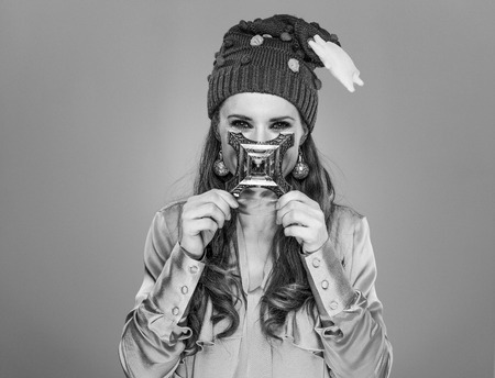 Stunning season. modern woman in funny Christmas hat isolated on grey background holding Eiffel Tower in front of faceの写真素材