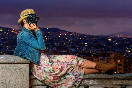 Perfect evening with stunning view. modern tourist woman in long dress and straw hat in Barcelona,...