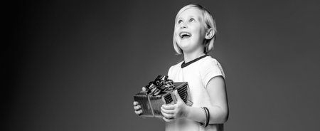 Modern Girl. happy trendy child in white dress isolated on grey background with Christmas present...