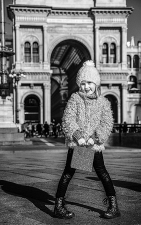 Full length portrait of elegant girl with red shopping bag at Piazza del Duomo in Milan, Italy standingの写真素材