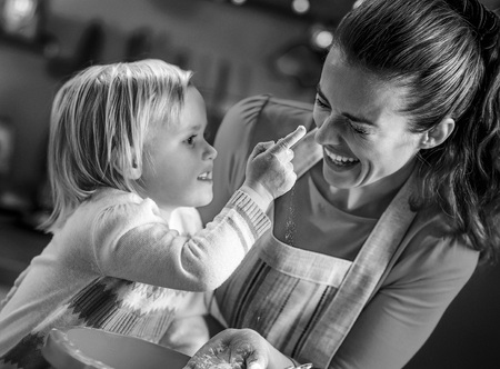 Baby trying to smear mothers nose with flour while making christmas cookiesの写真素材