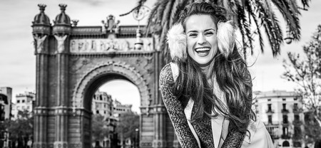in Barcelona for a perfect winter. Portrait of happy elegant woman in earmuffs in Barcelona, Spain standing near Arc de Triomの写真素材
