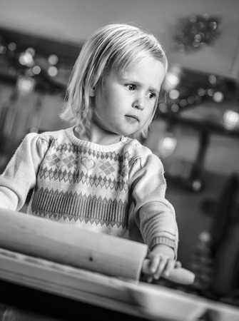 Portrait of baby rolling pin dough in christmas decorated kitchenの写真素材