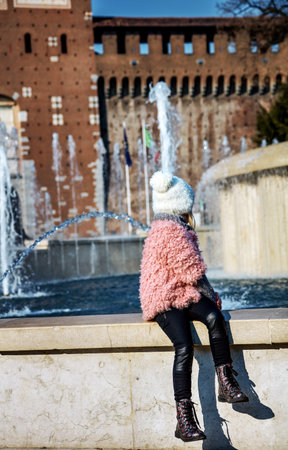 Rediscovering things everybody love in Milan. Seen from behind modern child near Sforza Castle in Milan, Italy looking at fontainの写真素材