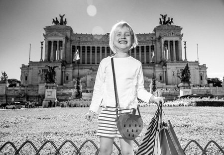 Roman Holiday. Portrait of happy modern girl in the front of Palazzo Venezia in Rome, Italy with shopping bagsの写真素材