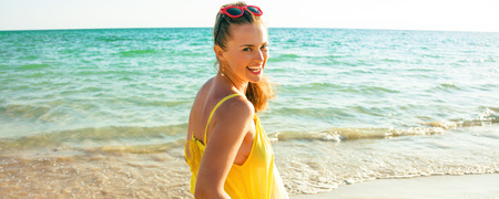 Colorful and wonderfully cheerful mood. Portrait of smiling young woman in colorful dress on the beach in the eveningの写真素材