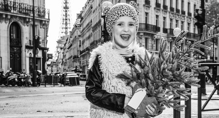 Boiling hot trendy winter in Paris. Full length portrait of smiling modern child with Christmas tree in Paris, Franceの写真素材