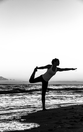 Refreshing wild sea side workout. Silhouette. Full length portrait of active woman in sport clothes on the seacoast stretchingの写真素材