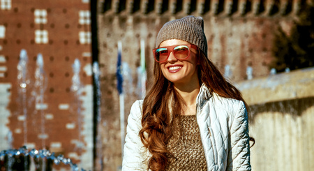 Rediscovering things everybody love in Milan. smiling trendy woman in front of Sforza Castle in Milan, Italy sitting near fountainの写真素材