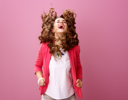 Pink Mood. smiling stylish woman with long wavy brunette hair isolated on pink shaking hairの写真素材