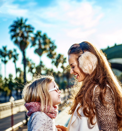 in Barcelona for a perfect winter. smiling modern mother and daughter tourists on embankment in Barcelona, Spain looking at each otherの写真素材