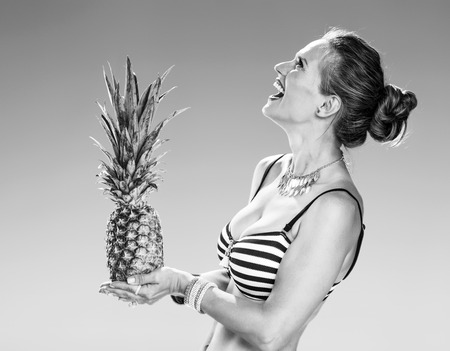 Perfect summer. smiling young woman in beachwear on the seacoast with pineapple looking at copy spaceの写真素材