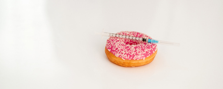 Closeup on donut and diabetes syringe on tableの写真素材