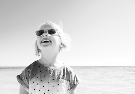 Colorful and wonderfully cheerful mood. Portrait of happy trendy girl in colorful shirt on the seacoast looking at copy spaceの写真素材