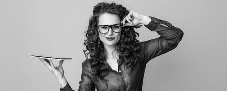 trendy woman with long wavy brunette hair with tablet PC on background