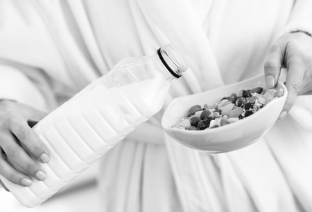 Closeup on woman pouring milk into plate with oatmealの写真素材