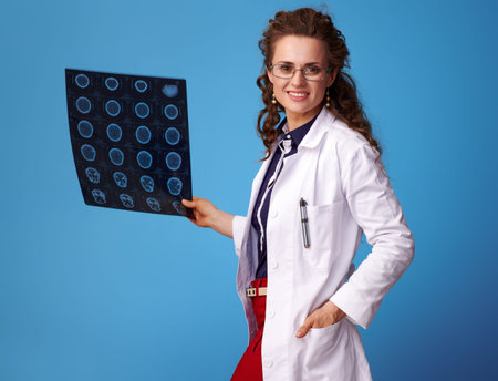 medical practitioner woman in white medical robe with a tomography isolated on blue