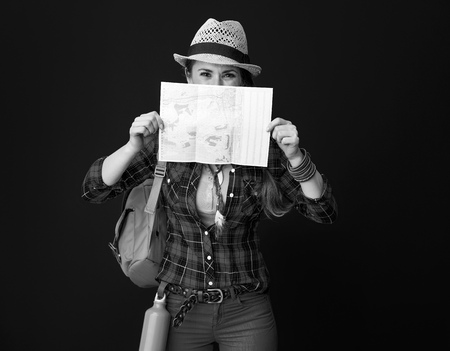 Searching for inspiring places. active traveller woman with backpack hiding behind map against backgroundの写真素材