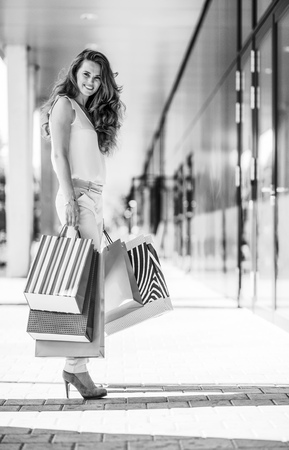 Full length portrait of happy young woman with shopping bags on the mall alleyの写真素材