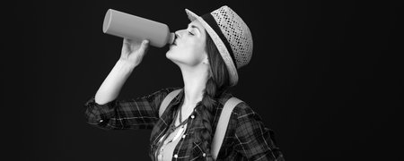 Searching for inspiring places. fit tourist woman in a plaid shirt drinking water from bottle...