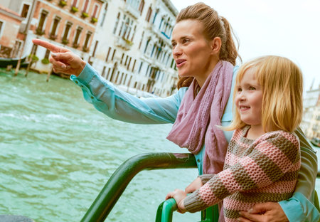 Baby girl and mother poiting while travel by vaporetto in venice, italyの写真素材